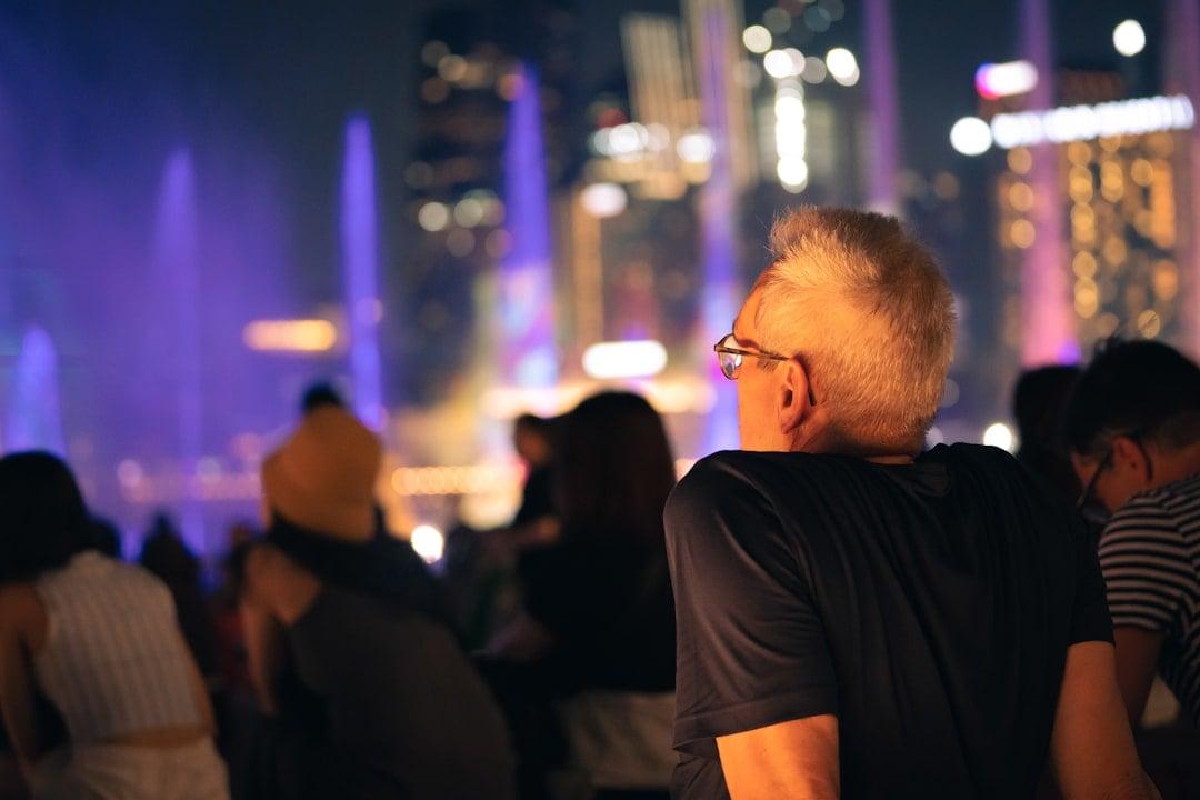 People watch a fountain show at night. | Photo by Soroush H. Zargarbashi on Unsplash
