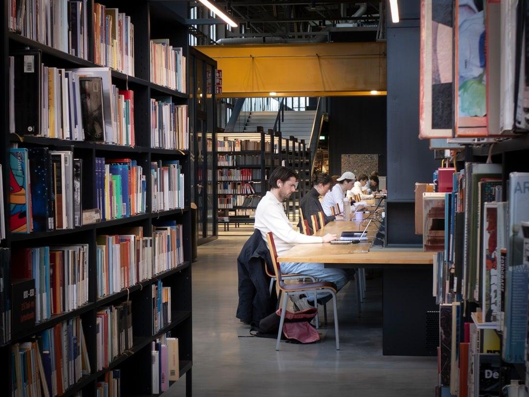 Open research books and laptop on a wooden desk in soft natural light