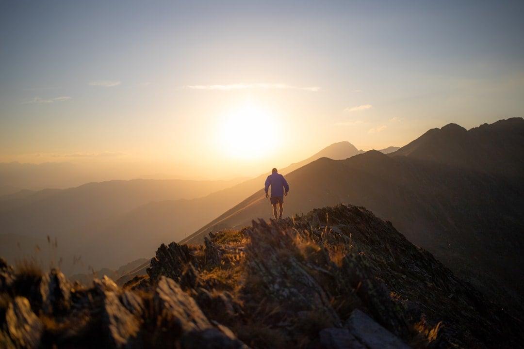 Person standing at the edge of a misty mountain ridge at sunrise